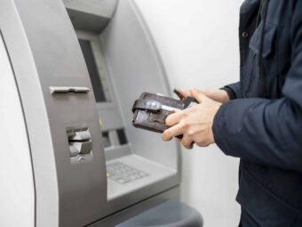 persons hand hold a wallet with cash and withdraw some money in atm